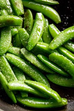 green beans in a frying pan with water droplets on the top and bottom, ready to be cooked