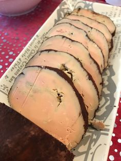 slices of sliced meat sitting on top of a white plate next to a red tablecloth