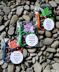 three bags of scissors sitting on top of some rocks and stones with tags attached to them