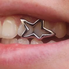 a close up of a person's teeth with a silver star on it