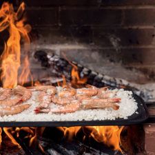 shrimp and rice cooking on an outdoor grill with fire in the backgroung