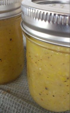 two jars filled with yellow liquid sitting on top of a table next to each other