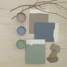 some paint samples and other items on a white wooden surface with branches in the background