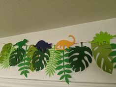 some paper cut out animals and plants on a string with leaves hanging from it's sides