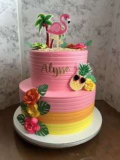 a pink cake with flamingos and pineapples on top is sitting on a table