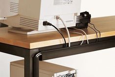 a computer sitting on top of a wooden desk next to a white box with wires