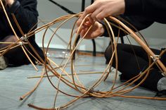 two people sitting on the floor working on some kind of art project with wires attached to them