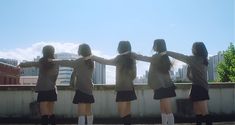 four girls in school uniforms are standing together