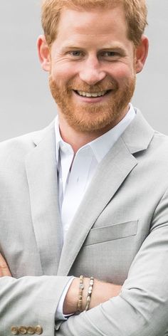 a close up of a person wearing a suit and smiling at the camera with his arms crossed