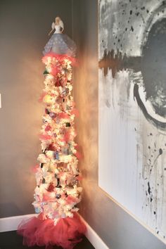 a christmas tree made out of teddy bears and other toys in a corner with a painting on the wall behind it