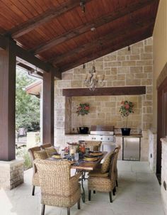 an outdoor dining area with wicker chairs and a grill on the back wall is shown