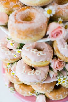 a pink plate topped with lots of donuts covered in frosted icing and flowers