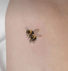 a small tattoo of a bee on the back of a woman's shoulder