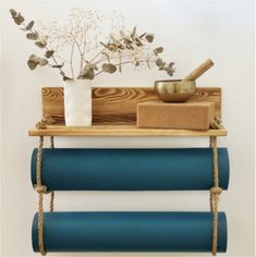 a wooden shelf holding yoga mats, a bowl and a vase with flowers on it