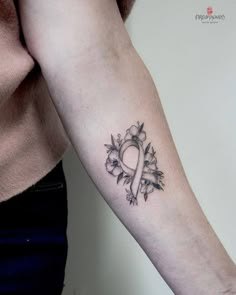 a woman's arm with a tattoo on it that has a white ribbon in the shape of a heart