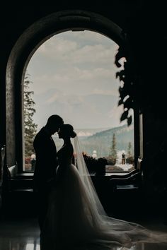 the bride and groom are kissing in front of an arched window at their wedding reception