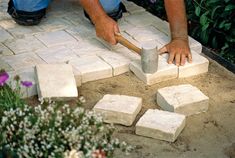 a man working with cement blocks in the garden