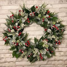 a wreath on a brick wall with greenery and berries