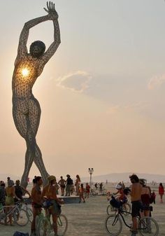 people are standing and riding bikes in front of a statue