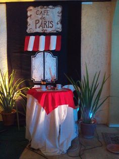 a table with a red and white cloth on it in front of a sign that says cafe de paris