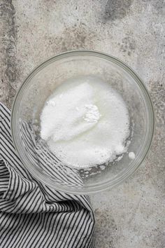 a glass bowl filled with flour next to a striped towel