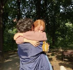 two people hugging each other in the woods