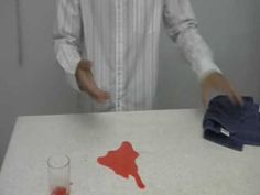 a man standing in front of a white table with red stains on it and a glass filled with liquid