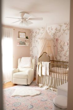 a baby's room with floral wallpaper and a white chair in the corner