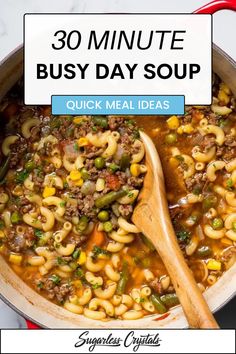 a large pot filled with pasta and vegetables, next to a wooden spoon on top of it