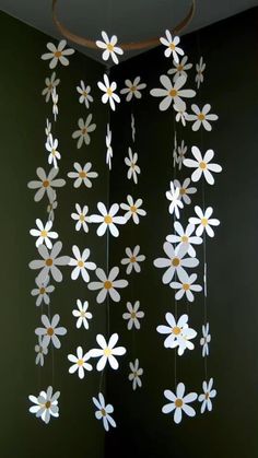 some white flowers hanging from the ceiling in a room with green walls and black flooring