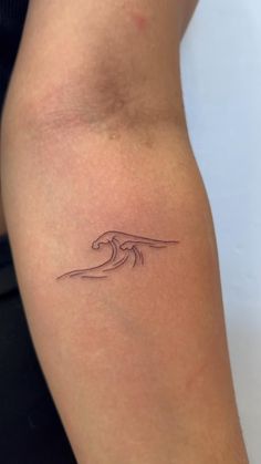 a small wave tattoo on the back of a woman's right arm and leg