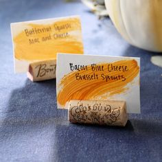 two pieces of paper with writing on them sitting on a table next to pumpkins