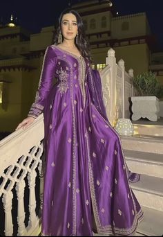 a woman in a purple dress standing on some stairs