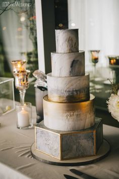 a three tiered cake sitting on top of a table next to candles and flowers