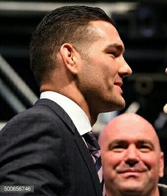 a man in a suit and tie standing next to another man with his hand on his chin