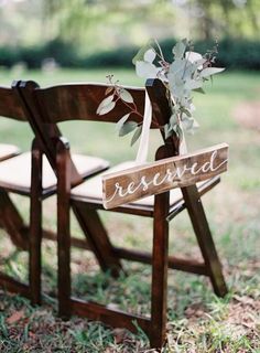 a wooden chair with a sign that says reserved on the seat and flowers in it