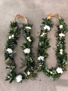 two wreaths with white flowers and greenery are laid out on the floor next to each other