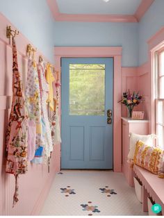 a blue door and pink walls in a room with towels hanging on the hooks,