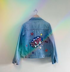 This stunning jacket is a totally one of a kind, unique piece. If you are going to a festival this summer, you will not see anyone else wearing a jacket like this !  Crafted using a pre-loved jacket, preventing waste and potential land fill, customised and embellished by me, in my little design studio in Wales. Decorated with iron on patches, sequins, gems, and fabulous neon arm tassels, this jacket with really make you stand out in a crowd.  jacket is UK size 12-14, casual fit.  length collar t Long Sleeve Graphic Print Denim Jacket For Summer, Graphic Print Long Sleeve Denim Jacket For Summer, Trendy Medium Wash Outerwear For Festival, Summer Long Sleeve Denim Jacket With Graphic Print, Summer Denim Jacket With Graphic Print And Long Sleeves, Festival Long Sleeve Denim Jacket With Pockets, Trendy Denim Festival Outerwear, Trendy Denim Outerwear For Festivals, Trendy Denim Jacket For Fall Festival