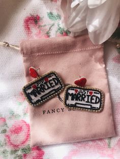 two embroidered badges sitting on top of a piece of pink fabric next to a white flower