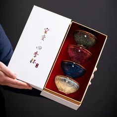 a person holding an open box with three bowls in it