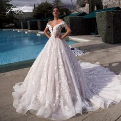 a woman standing in front of a pool wearing a wedding dress with flowers on it