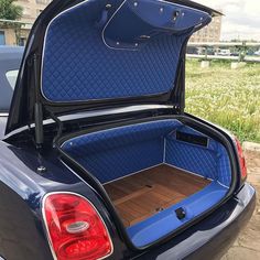 the back end of a blue car with its trunk open