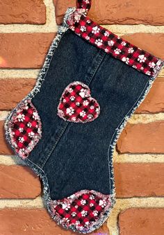 an old pair of jean shorts decorated with red and white flowers on the side of a brick wall