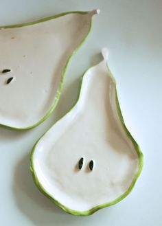 two white and green pear shaped dishes sitting on top of a table next to each other