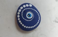 a blue and white painted rock with an evil eye on it