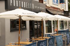 an outdoor cafe with tables and umbrellas outside