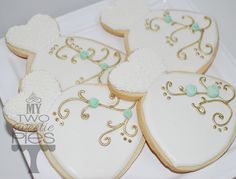 decorated heart shaped cookies on a white plate with gold trimmings and blue accents