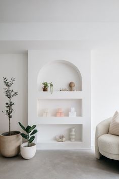 a living room filled with furniture and a potted plant next to a white wall