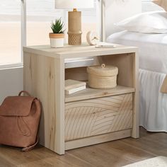 a white bed sitting next to a wooden table with a bag on top of it